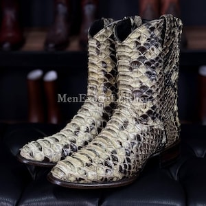 Könnte beinhalten: Cowboy-Stiefel mit Schlangenmuster in Beige, Braun und Schwarz. Die Stiefel haben eine spitze Zehenpartie und einen gestapelten Absatz. Der Text "MenExoticLeather" ist auf dem Bild sichtbar. Sie bestehen aus einem strukturierten Material.