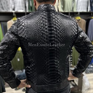 Pode incluir: Casaco de couro preto com padr&atilde;o de pele de cobra. O casaco tem gola alta e silhueta ajustada. O texto "MenExoticLeather" &eacute; vis&iacute;vel no casaco. &Eacute; uma pe&ccedil;a de roupa exterior elegante.