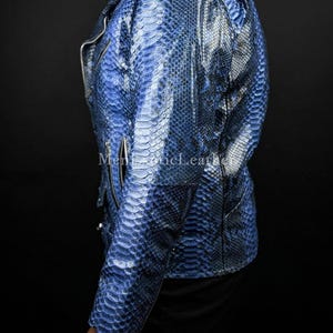 Puede incluir: Chaqueta de cuero azul con textura de piel de serpiente y cierre de cremallera plateada. La chaqueta tiene un estilo motero cl&aacute;sico con cuello con muescas y mangas largas. El texto "Men Exotic Leather" es visible en la chaqueta.
