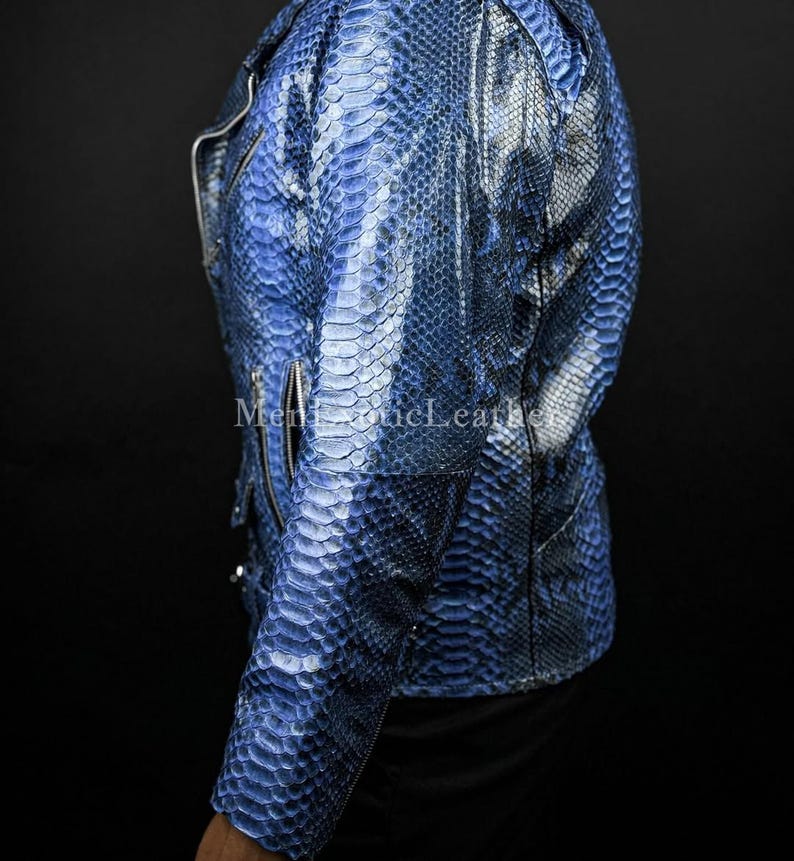 Puede incluir: Chaqueta de cuero azul con textura de piel de serpiente y cierre de cremallera plateada. La chaqueta tiene un estilo motero cl&aacute;sico con cuello con muescas y mangas largas. El texto "Men Exotic Leather" es visible en la chaqueta.