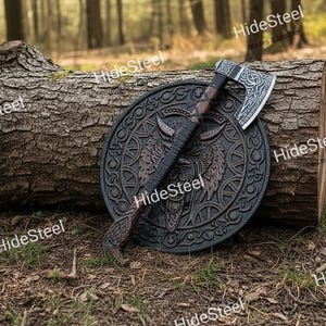May include: A Viking-style axe and shield set. The axe has a silver blade with intricate designs and a wooden handle. The shield is round, black, and features a detailed wolf design. The set is displayed on a log in a forest setting.