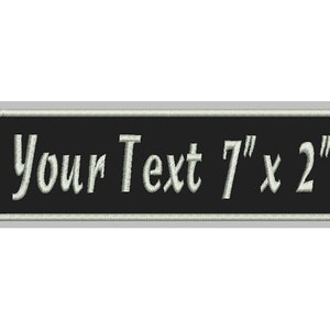 May include: Black embroidered patch with white text that reads "Your Text 7" x 2" ".