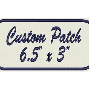 May include: A white rectangular patch with a navy blue border and the text "Custom Patch 6.5" x 3" in navy blue cursive font.