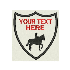 May include: A black and white silhouette of a person riding a horse inside a black shield with a red border. The text "YOUR TEXT HERE" is written in red inside the shield.