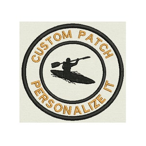 Peut inclure: Patch brodé noir et or avec une silhouette d'une personne en kayak. Le patch a le texte "CUSTOM PATCH PERSONALIZE IT" autour du bord.