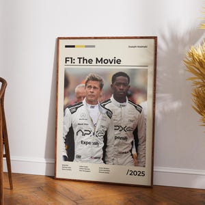 Könnte beinhalten: Ein gerahmtes Filmplakat für "F1: The Movie" mit zwei Männern in Rennanzügen. Das Poster hat einen cremefarbenen Hintergrund mit dem Titel oben und dem Jahr 2025 unten. Die Männer tragen weiße Rennanzüge mit schwarzen Akzenten.