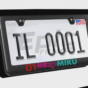 May include: Black license plate frame with a white license plate. The plate reads "IL 0001" in black. The frame has the text "Epic Fanatics" and a small American flag. The bottom of the plate has the text "01 初音ミク MIKU".