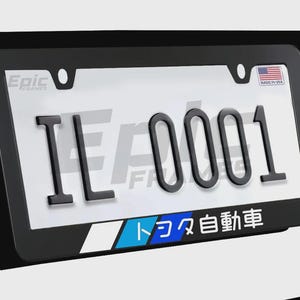 May include: Black license plate frame with the letters "IL 0001" in black. The frame has the text "Epic Frames" and "Made in USA" with the American flag. The bottom of the frame has Japanese text and blue and white accents.