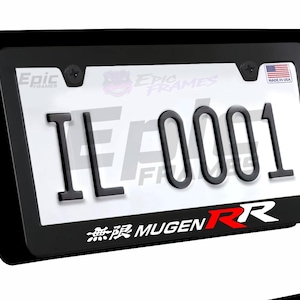 May include: Black license plate frame with the text "IL 0001". The frame has the text "Epic Frames" and "MUGEN RR" in white and red. A small American flag sticker is in the upper right corner.