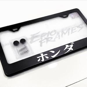 May include: Black license plate frame with the text "EPIC FRAMES" and Japanese characters. Includes mounting hardware. The frame is designed to fit a standard 12 x 6 inch license plate.