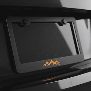 May include: A white ceramic mug with a black handle and the text "But First, Coffee" in a bold, black font. The mug is sitting on a wooden surface. The mug is approximately 4 inches tall.