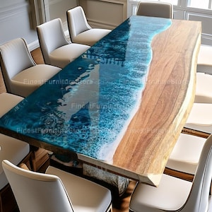 Könnte beinhalten: Ein rechteckiger Esstisch mit einzigartigem Design, der auf einer Seite einen blauen Harz-Ozean-Effekt und auf der anderen Seite Naturholz aufweist. Der Tisch ist von weißen Stühlen umgeben und bildet eine moderne und elegante Essgruppe.