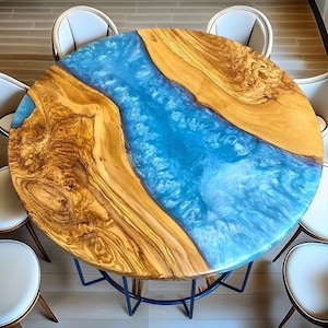 May include: A circular wooden table featuring a blue resin river design. The table showcases a natural wood grain pattern with a blue resin river flowing through the centre. It is supported by a blue metal base.