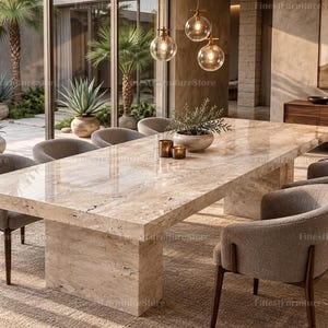 May include: A large rectangular dining table with a polished beige travertine stone top and a matching pedestal base, surrounded by eight upholstered armchairs with dark wooden legs, featuring a small potted plant and two candles on the surface.