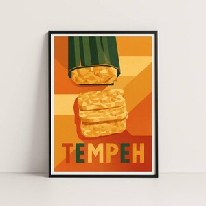 Puede incluir: Una impresión artística enmarcada con una ilustración estilizada de tempeh. La obra de arte muestra una pila de tempeh y un paquete de tempeh sobre un fondo cálido naranja y amarillo. La palabra "TEMPEH" está impresa en negrita.