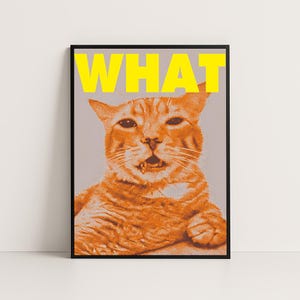 Puede incluir: Una impresión artística enmarcada que presenta un gato atigrado naranja con la boca abierta, como sorprendido. La palabra "WHAT" está impresa en letras amarillas grandes sobre la cabeza del gato. La obra de arte tiene un patrón de puntos de semitono y está sobre un fondo gris.