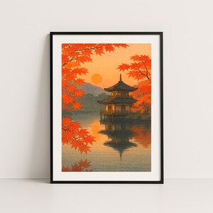 Puede incluir: Impresión artística enmarcada que representa una pagoda japonesa reflejada en agua tranquila. La escena está enmarcada por vibrantes hojas de arce naranja, con un sol poniente al fondo. La obra evoca una sensación de tranquilidad y belleza natural.