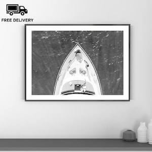 May include: Black and white framed print of a luxury yacht sailing on the ocean. The image is taken from an aerial perspective, showing the boat's bow cutting through the water. The words "FREE DELIVERY" are printed in black above the frame.