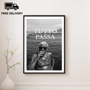 May include: A black and white framed wall art print featuring a shirtless person wearing dark sunglasses, smoking a cigarette, with the text TUTTO PASSA printed in white over the sea and again as a tattoo on the person's chest.