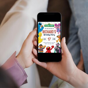 May include: A black smartphone displays a colorful Sesame Street birthday party invitation. The invitation features the text "RICHARD'S Birthday Party" with the date June 17 and the time 6 PM. Sesame Street characters are also visible.