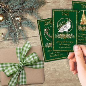 Yule Oracle reading spread of two cards placed on a wooden table.  A hand holding a third card is about to place it on the table.  the three cards are Antler, Owl, and Tree.