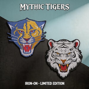 Op de afbeelding: Twee geborduurde patches met tijgergezichten. Eén is blauw en goud, de andere is wit met zwarte strepen. Beide hebben open monden met zichtbare tanden. De tekst "MYTHIC TIGERS" staat bovenaan en "IRON-ON • LIMITED EDITION" onderaan.