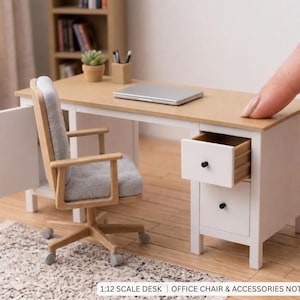 Puede incluir: Un escritorio en miniatura a escala 1:12 con una superficie de madera clara y estructura blanca, que cuenta con dos cajones con pomos negros, uno de ellos abierto. El escritorio incluye una silla de oficina de madera clara con asiento gris.