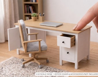 May include: A miniature 1:12 scale desk with a light wood-toned top and white frame, featuring two drawers with black knobs, one of which is open. The desk is accompanied by a light wood office chair with a grey upholstered seat and backrest.