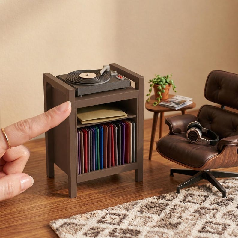 Pu&ograve; includere: Un supporto in miniatura in legno marrone per giradischi con un piatto sulla parte superiore, un ripiano centrale con una busta beige e un ripiano inferiore pieno di una collezione di dischi in vinile colorati, accanto a una poltrona marrone.