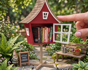 May include: A 1:12 scale miniature community book library featuring a red structure with a tan roof, a white window frame, and a hinged door. The interior contains miniature books. A small sign reads LITTLE FREE LIBRARY in white text.