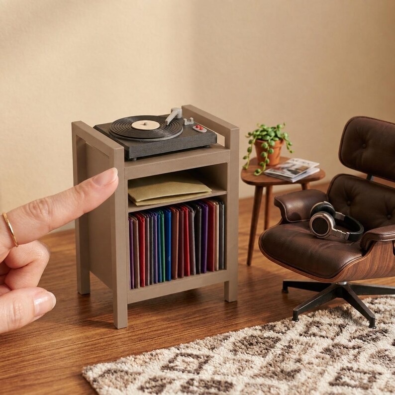 Pu&ograve; includere: Un supporto in miniatura grigio per giradischi con un piatto rotante sulla parte superiore, un ripiano centrale con una busta beige e un ripiano inferiore pieno di dischi in vinile multicolore, accanto a una poltrona marrone.