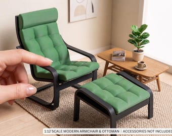 May include: A 1:12 scale miniature armchair and ottoman set featuring black frames and tufted green cushions. The furniture pieces have a sleek, low-profile design with a high backrest on the chair. Text at the bottom reads 1:12 SCALE MODERN ARMCHAIR & OTTOMAN | ACCESSORIES NOT INCLUDED.