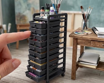 May include: A dark grey miniature art cart featuring ten sliding storage trays. The unit is designed in a 1:12 scale and includes a top shelf for supplies. The text on the image reads: 1:12 SCALE ART CART WITH 10 TRAYS | ACCESSORIES NOT INCLUDED.
