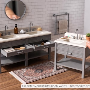 May include: A 1:12 scale miniature bathroom vanity set in gray with a white countertop, featuring two sinks on the larger unit and one on the smaller unit, with open drawers and shelves. The text reads 1:12 SCALE MODERN BATHROOM VANITY | ACCESSORIES NOT INCLUDED.