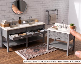 May include: A 1:12 scale miniature bathroom vanity set in grey with a white countertop, featuring two sinks on the larger unit and one on the smaller unit, with open drawers and shelves. The text reads 1:12 SCALE MODERN BATHROOM VANITY | ACCESSORIES NOT INCLUDED.