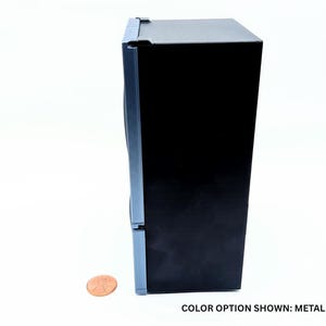 May include: A miniature refrigerator model in a metallic gray finish with a black side panel. The unit features a vertical door design and is positioned next to a copper penny for scale. The text at the bottom reads: COLOR OPTION SHOWN: METALLIC GRAY.