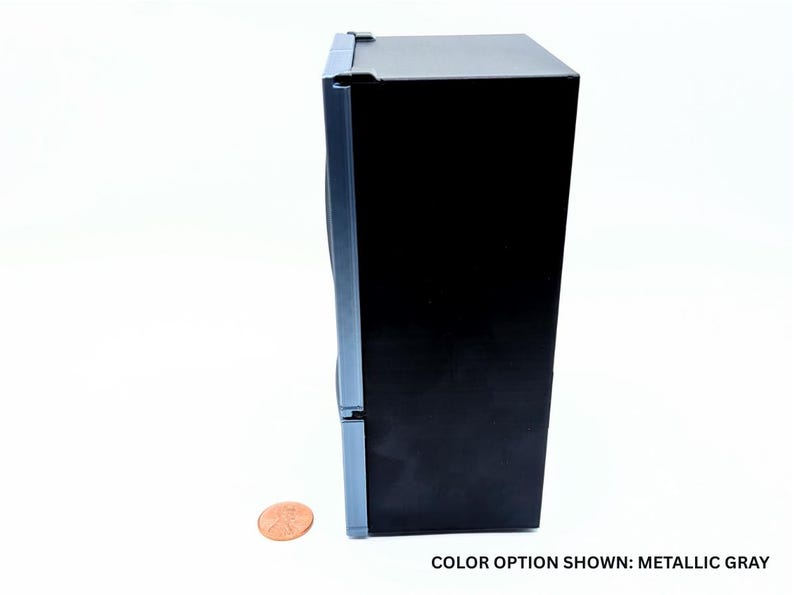 May include: A miniature refrigerator model in a metallic gray finish with a black side panel. The unit features a vertical door design and is positioned next to a copper penny for scale. The text at the bottom reads: COLOR OPTION SHOWN: METALLIC GRAY.