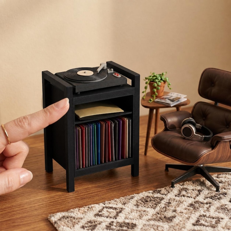 Pu&ograve; includere: Una console giradischi in miniatura nera con un piatto rotante sulla parte superiore, un ripiano centrale con un oggetto piatto e un ripiano inferiore riempito con una fila di dischi in vinile colorati, accanto a una poltrona in miniatura marrone.