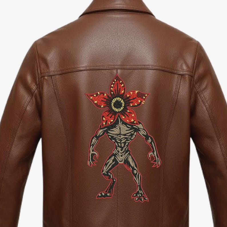 Pode incluir: Casaco de couro castanho com um patch Demogorgon nas costas. O patch apresenta uma cabe&ccedil;a vermelha em forma de flor com um centro amarelo e um corpo cinzento musculoso. O casaco tem uma gola cl&aacute;ssica e um corte sob medida.