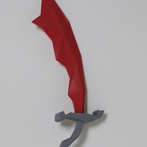 May include: A geometric, abstract sculpture of a sword. The blade is a vibrant red, while the handle and guard are gray. The design features sharp angles and a modern aesthetic, mounted against a white background.