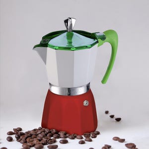 May include: A red, white, and green stovetop espresso maker with a silver band and handle. Coffee beans are scattered around the base of the coffee maker. The coffee maker has a geometric design.