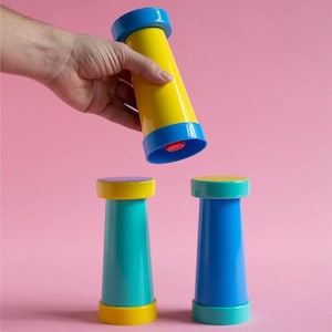 May include: Three cylindrical objects with flared ends. One is yellow with blue caps, one is teal with yellow caps, and one is blue with teal caps. Each object features a smooth, solid-coloured plastic finish and a slightly tapered central body.