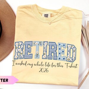 May include: A pale yellow short-sleeve t-shirt featuring the word RETIRED in large block letters with alternating floral, blue gingham, and polka dot patterns. Below the text, the phrase I worked my whole life for this T-shirt 2026 is printed.