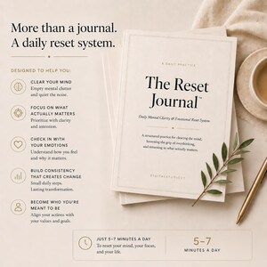 May include: A stack of cream-colored journals titled "The Reset Journal" with gold accents. The cover text includes "Daily Mental Clarity & Emotional Reset System." A sprig of greenery and a gold pen are placed nearby.
