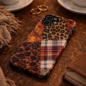 Puede incluir: Funda de teléfono estampada con un diseño de patchwork. La funda presenta secciones de estampado de leopardo, cuadros y patrones marrones texturizados. Dos anillos dorados y dos tazas de café en el fondo.
