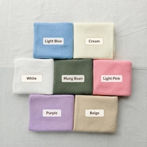 May include: A collection of seven rectangular fabric swatches arranged in a grid, featuring colours labelled as Light Blue, Cream, White, Mung Bean, Light Pink, Purple, and Beige. Each piece of fabric displays a consistent, fine-ribbed texture.