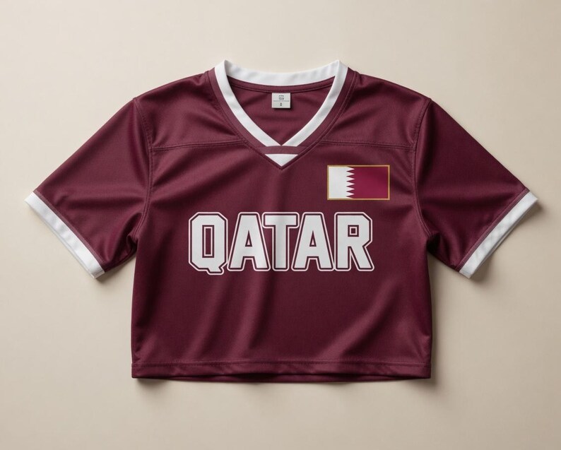 Peut inclure: Un maillot de corps bordeaux avec des bordures blanches sur les manches et l'encolure. Le mot "QATAR" est imprim&eacute; en grandes lettres blanches sur la poitrine. Un petit &eacute;cusson du drapeau du Qatar est sur le c&ocirc;t&eacute; droit.