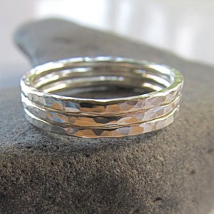 Peut inclure: Trois bagues empilables en argent martelé. Les bagues sont fines et ont une surface texturée.
