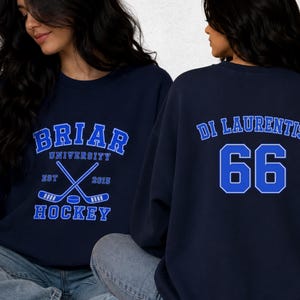 Op de afbeelding: Marineblauw sweatshirt met de tekst "BRIAR UNIVERSITY HOCKEY" in blauw en wit. De achterkant van het sweatshirt toont "DI LAURENTIS 66" in blauw en wit. Het sweatshirt is een casual stijl.