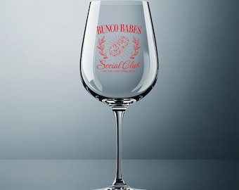 Puede incluir: Una copa de vino transparente con un tallo largo, con texto rojo que dice "Bunco Babes Social Club" con dados y acentos de hojas. También se incluye la frase "Let the good times roll".